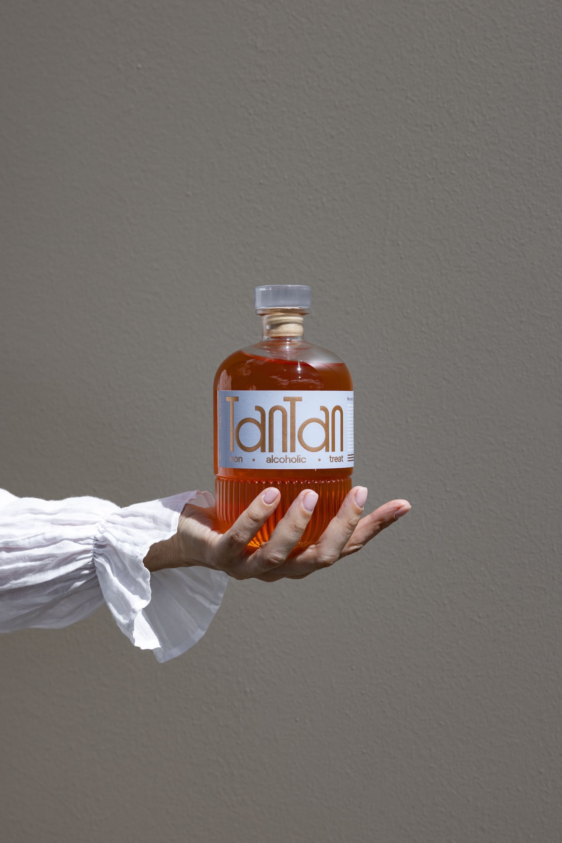 Mano che regge una bottiglia TANTAN aperitivo analcolico