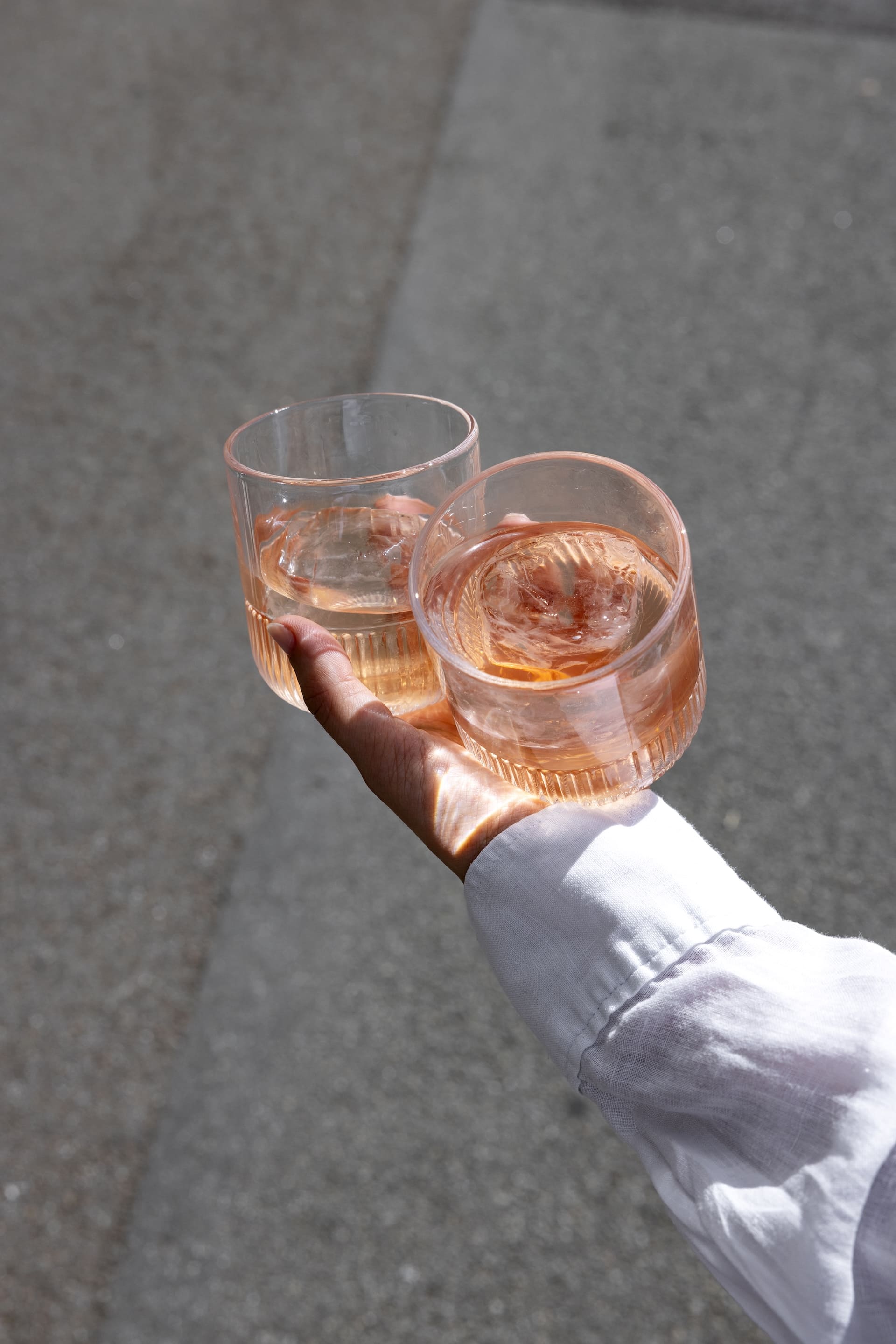 Mano che regge due bicchieri TANTAN aperitivo analcolico agli agrumi
