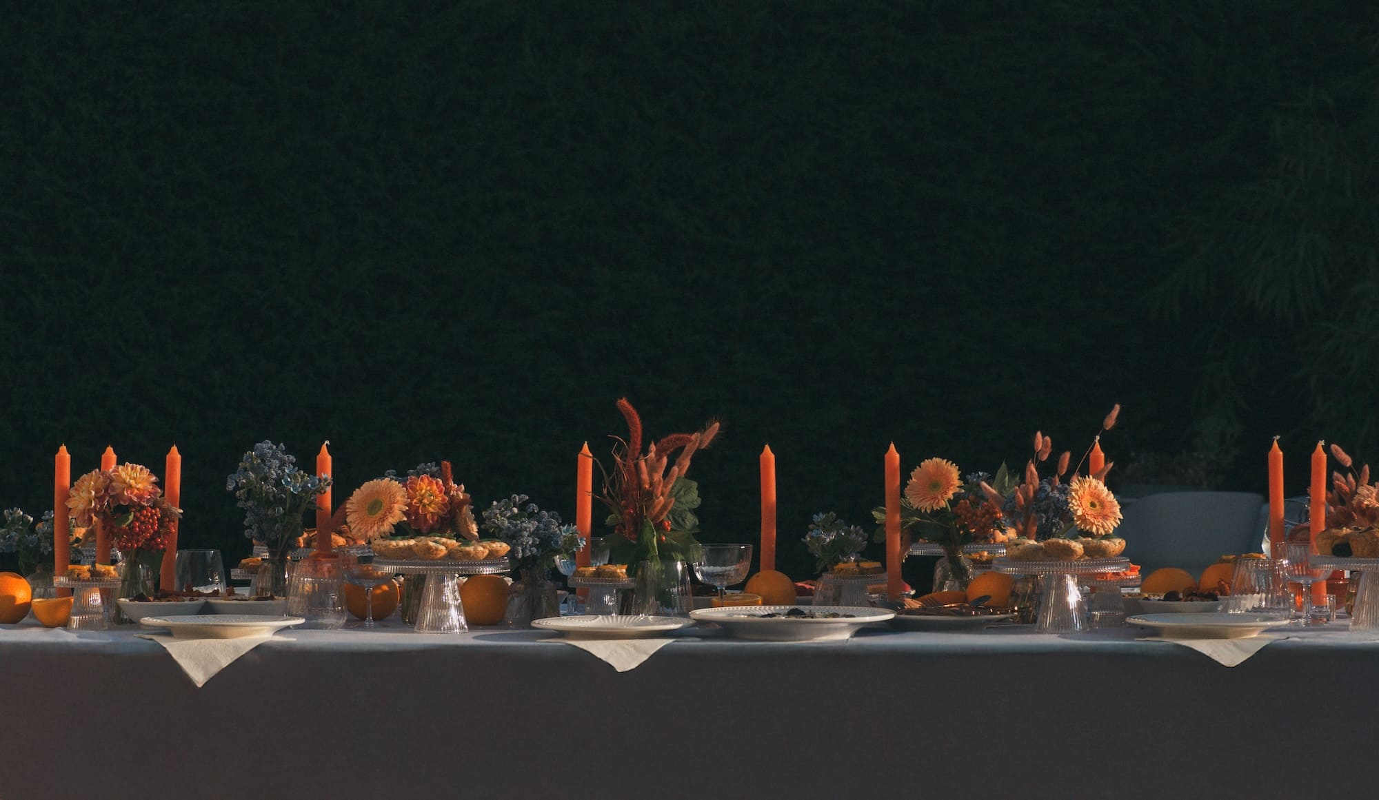 Tavola imbandita per un aperitivo estivo nei toni arancione e azzurro con fiori e candele per Tantan aperitivo analcolico